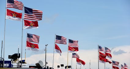 CHARLOTTE, NC - MAY 21:  Flags fly on top of haulers in the garage area during practice for the NASCAR Sprint Cup Series Coca-Cola 600 at Charlotte Motor Speedway on May 21, 2015 in Charlotte, North Carolina.  (Photo by Streeter Lecka/Getty Images) | Getty Images