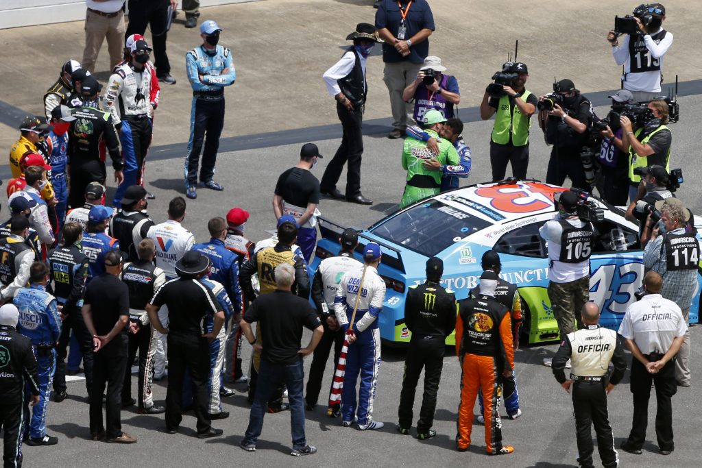 TALLADEGA, ALABAMA - JUNE 22: NASCAR drivers stand in solidarity with Bubba Wallace, driver of the #43 Victory Junction Chevrolet, during pre-race ceremonies prior to the NASCAR Cup Series GEICO 500 at Talladega Superspeedway on June 22, 2020 in Talladega, Alabama. A noose was found in the garage stall of NASCAR driver Bubba Wallace at Talladega Superspeedway a week after the organization banned the Confederate flag at its facilities. (Photo by Brian Lawdermilk/Getty Images) | Getty Images