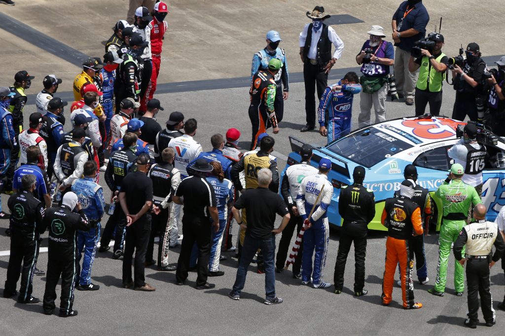 TALLADEGA, ALABAMA - JUNE 22: NASCAR drivers stand in solidarity with Bubba Wallace, driver of the #43 Victory Junction Chevrolet, during pre-race ceremonies prior to the NASCAR Cup Series GEICO 500 at Talladega Superspeedway on June 22, 2020 in Talladega, Alabama. A noose was found in the garage stall of NASCAR driver Bubba Wallace at Talladega Superspeedway a week after the organization banned the Confederate flag at its facilities. (Photo by Brian Lawdermilk/Getty Images) | Getty Images