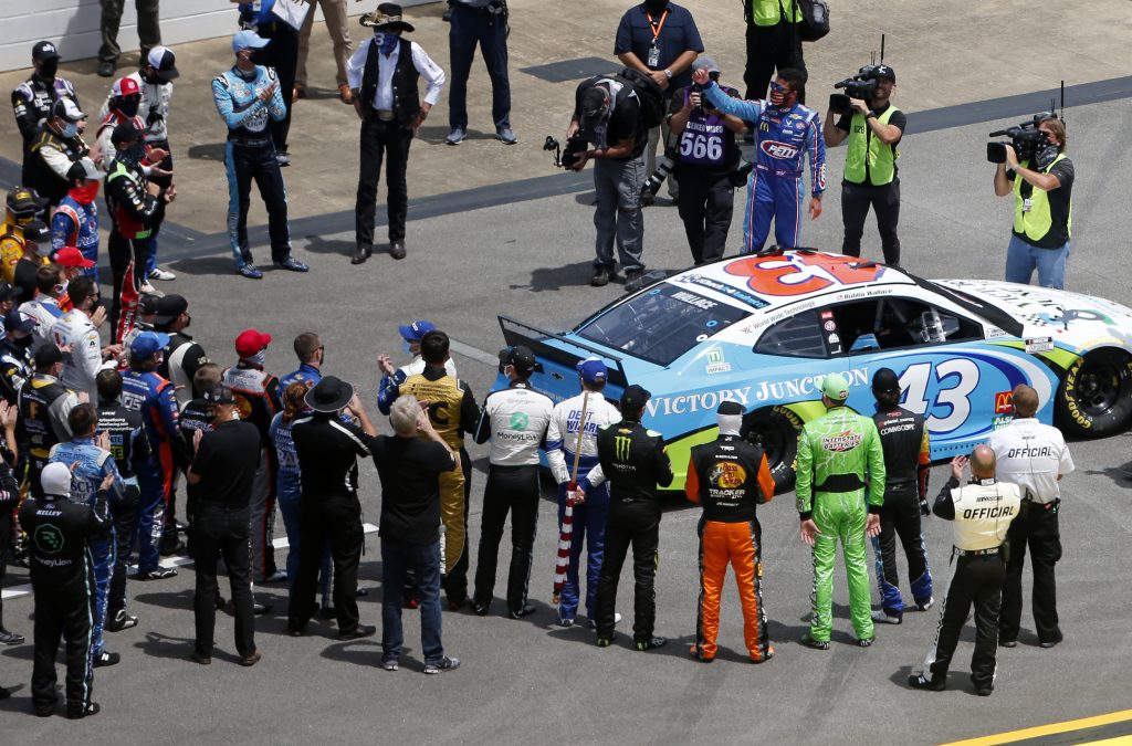TALLADEGA, ALABAMA - JUNE 22: NASCAR drivers stand in solidarity with Bubba Wallace, driver of the #43 Victory Junction Chevrolet, during pre-race ceremonies prior to the NASCAR Cup Series GEICO 500 at Talladega Superspeedway on June 22, 2020 in Talladega, Alabama. A noose was found in the garage stall of NASCAR driver Bubba Wallace at Talladega Superspeedway a week after the organization banned the Confederate flag at its facilities. (Photo by Brian Lawdermilk/Getty Images) | Getty Images