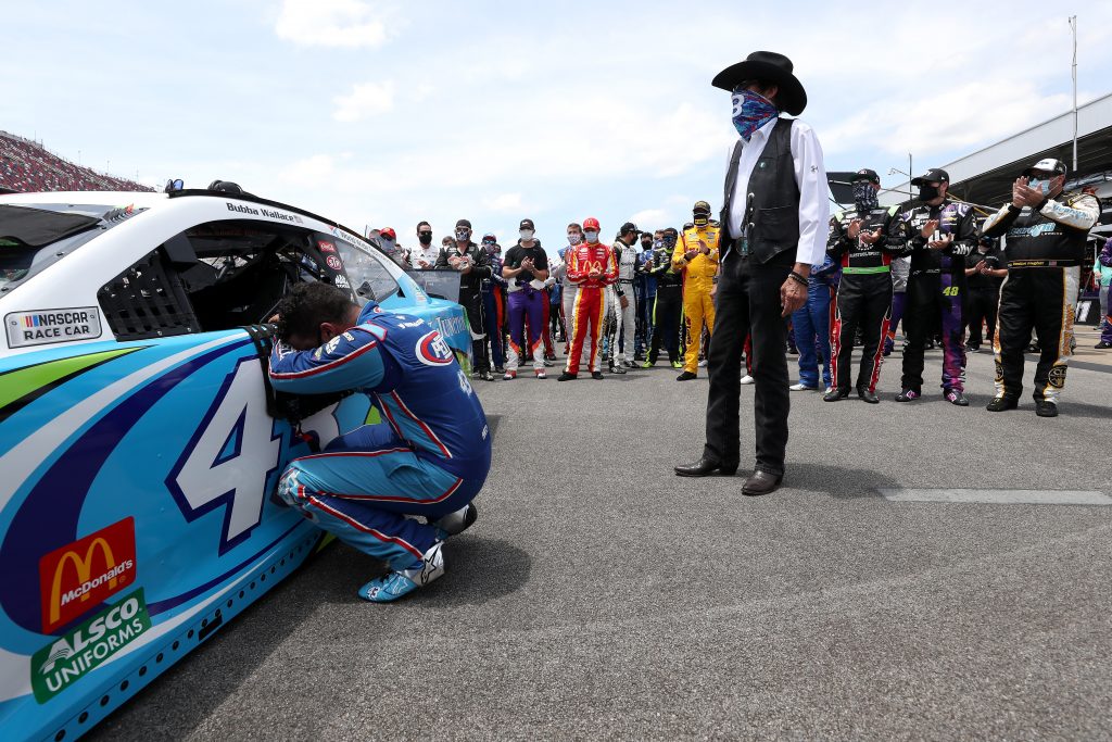 TALLADEGA, ALABAMA - JUNE 22: Bubba Wallace, driver of the #43 Victory Junction Chevrolet, kneels as team owner, and NASCAR Hall of Famer Richard Petty and NASCAR drivers stand in solidarity with Wallace prior to the NASCAR Cup Series GEICO 500 at Talladega Superspeedway on June 22, 2020 in Talladega, Alabama. A noose was found in the garage stall of NASCAR driver Bubba Wallace at Talladega Superspeedway a week after the organization banned the Confederate flag at its facilities. (Photo by Chris Graythen/Getty Images) | Getty Images