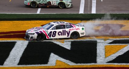 LAS VEGAS, NEVADA - MARCH 06: Kyle Busch, driver of the #18 Ethel M Chocolates Toyota, drives by as Alex Bowman, driver of the #48 Ally Chevrolet, celebrates with a burnout on the infield grass after winning the NASCAR Cup Series Pennzoil 400 at Las Vegas Motor Speedway on March 06, 2022 in Las Vegas, Nevada. (Photo by Dylan Buell/Getty Images) | Getty Images