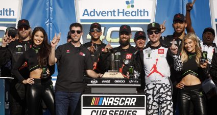 KANSAS CITY, KANSAS - MAY 15: Denny Hamlin, driver of the #11 Sport Clips Haircuts Toyota, and co-owner of 23XI Racing, Kurt Busch, driver of the #45 Jordan Brand Toyota, and crew celebrate in victory lane after winning the NASCAR Cup Series AdventHealth 400 at Kansas Speedway on May 15, 2022 in Kansas City, Kansas. (Photo by Chris Graythen/Getty Images) | Getty Images