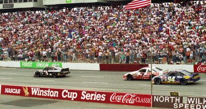NORTH WILKESBORO, NC - APRIL 12:  Dale Earnhardt driver of the #3 Goodwrench Chevrolet pulls past #7 Alan Kulwicki and #94 Terry Labonte in front of a standing crowd during the First Union 400 race on April 12, 1992 at the North Wilkesboro Speedway in North Wilkesboro, North Carolina. (Photo by Dozier Mobley/Getty Images)