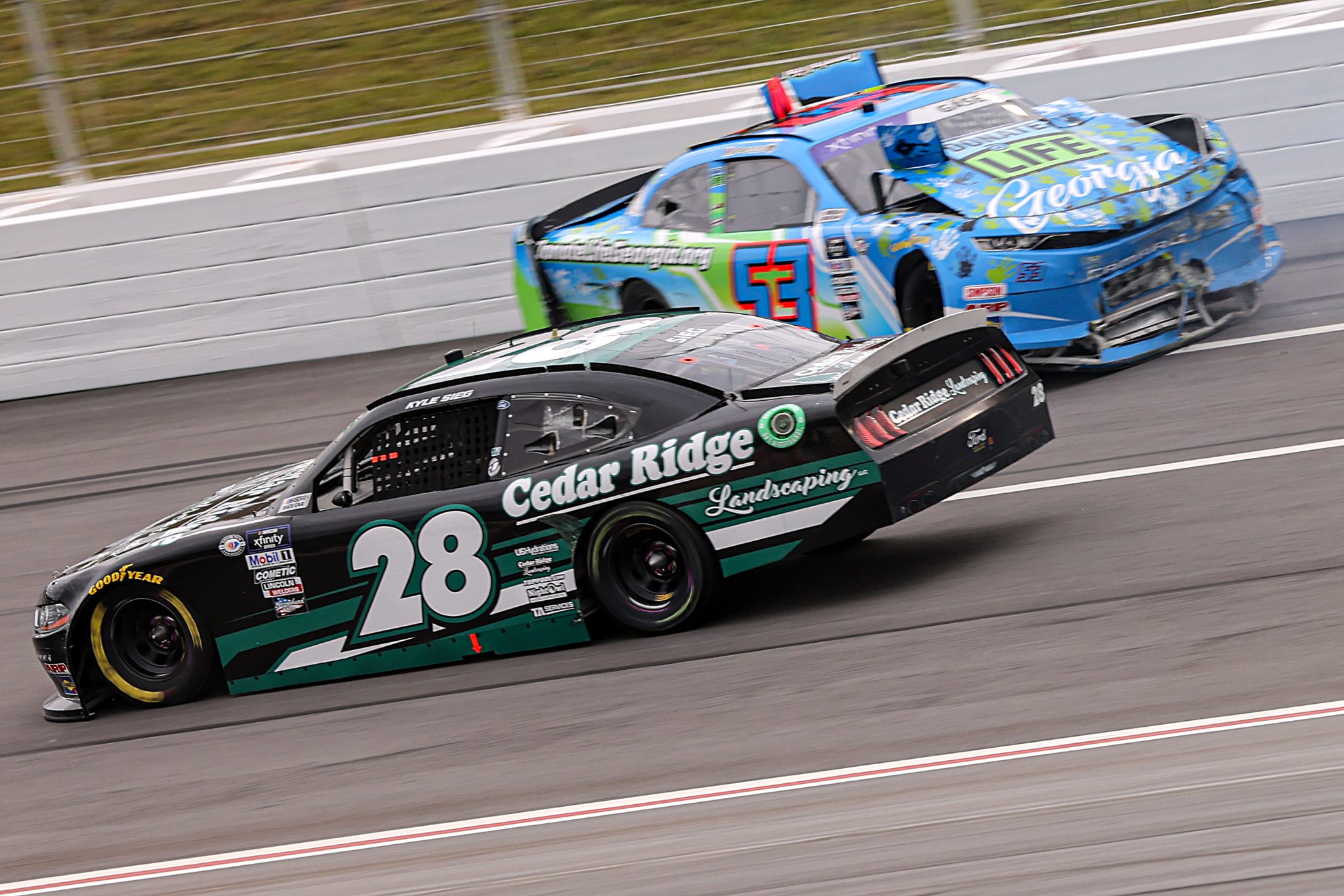 HAMPTON, GEORGIA - MARCH 18: Kyle Sieg, driver of the #28 Cedar Ridge Landscaping Ford, drives as Joey Gase, driver of the #53 Donate Life GA Chevrolet, spins in to the wall after an on-track incident during the NASCAR Xfinity Series RAPTOR 250 at Atlanta Motor Speedway on March 18, 2023 in Hampton, Georgia. (Photo by Jonathan Bachman/Getty Images) | Getty Images