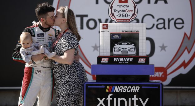 RICHMOND, VIRGINIA - APRIL 01: Chandler Smith, driver of the #16 Quick Tie Products Inc. Chevrolet, celebrates with a kiss from his wife, Kenzie Smith, holding son Chandler Smith Jr. in victory lane after winning the NASCAR Xfinity Series ToyotaCare 250 at Richmond Raceway on April 01, 2023 in Richmond, Virginia. (Photo by Jared C. Tilton/Getty Images) | Getty Images