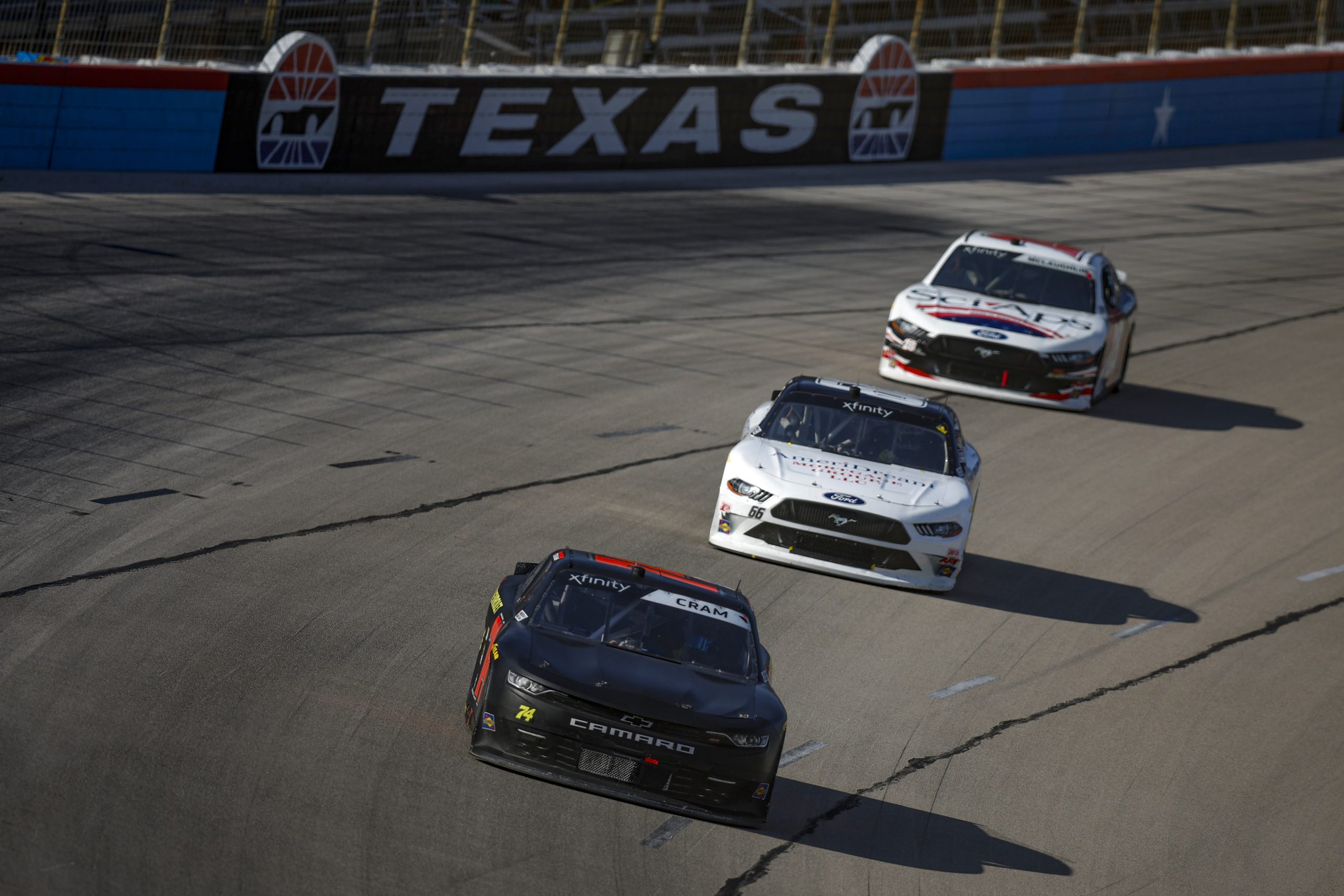 FORT WORTH, TEXAS - SEPTEMBER 23: Dawson Cram, driver of the #74 CHK Racing Chevrolet, Sage Karam, driver of the #66 Coble Enterprises Ford, and CJ McLaughlin, driver of the #28 Sci Aps Ford, race during the NASCAR Xfinity Series Andy's Frozen Custard 300 at Texas Motor Speedway on September 23, 2023 in Fort Worth, Texas. (Photo by Sean Gardner/Getty Images) | Getty Images