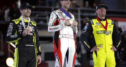 LOS ANGELES, CALIFORNIA - FEBRUARY 03: Denny Hamlin, driver of the #11 Sport Clips Haircuts Toyota, winner (C) Kyle Busch, driver of the #8 Morgan & Morgan Chevrolet, (R) second place and Ryan Blaney, driver of the #12 Menards/Great Lakes Flooring Ford, third place pose on the podium in victory lane after winning during the NASCAR Cup Series Busch Light Clash at The Coliseum at Los Angeles Memorial Coliseum on February 03, 2024 in Los Angeles, California. (Photo by Chris Graythen/Getty Images) | Getty Images
