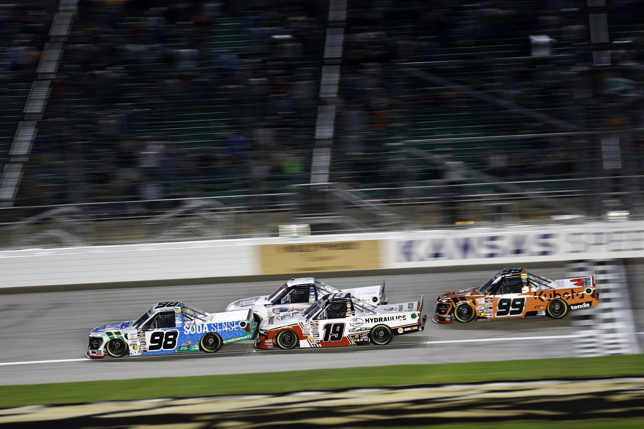 KANSAS CITY, KANSAS - SEPTEMBER 27: Ty Majeski, driver of the #98 Soda Sense/Curb Records Ford, leads Christian Eckes, driver of the #19 Gates Hydraulics Chevrolet, and Ben Rhodes, driver of the #99 Kubota Ford, to the to start the NASCAR Craftsman Truck Series Kubota Tractor 200 at Kansas Speedway on September 27, 2024 in Kansas City, Kansas. (Photo by Chris Graythen/Getty Images) | Getty Images