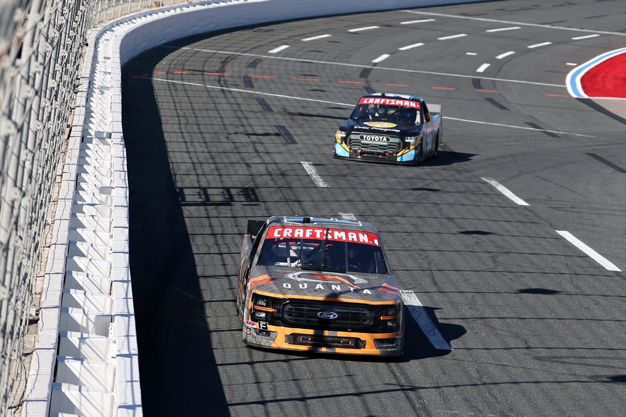 CONCORD, NORTH CAROLINA - OCTOBER 03: Jake Garcia, driver of the #13 Quanta Services Ford, and Timmy Hill, driver of the #56 Coble Enterprises/UNITS Toyota, race during the NASCAR Craftsman Truck Series EcoSave 250 at Charlotte Motor Speedway on October 03, 2025 in Concord, North Carolina. (Photo by David Jensen/Getty Images) | Getty Images