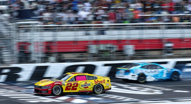 CONCORD, NORTH CAROLINA - OCTOBER 05: Joey Logano, driver of the #22 Shell Pennzoil Ford, crosses the finish line ahead of Ross Chastain, driver of the #1 Busch Light Chevrolet, who finishes in reverse after an on-track incident after an on-track incident to end the NASCAR Cup Series Bank of America ROVAL 400 at Charlotte Motor Speedway on October 05, 2025 in Concord, North Carolina. (Photo by Jared C. Tilton/Getty Images) | Getty Images