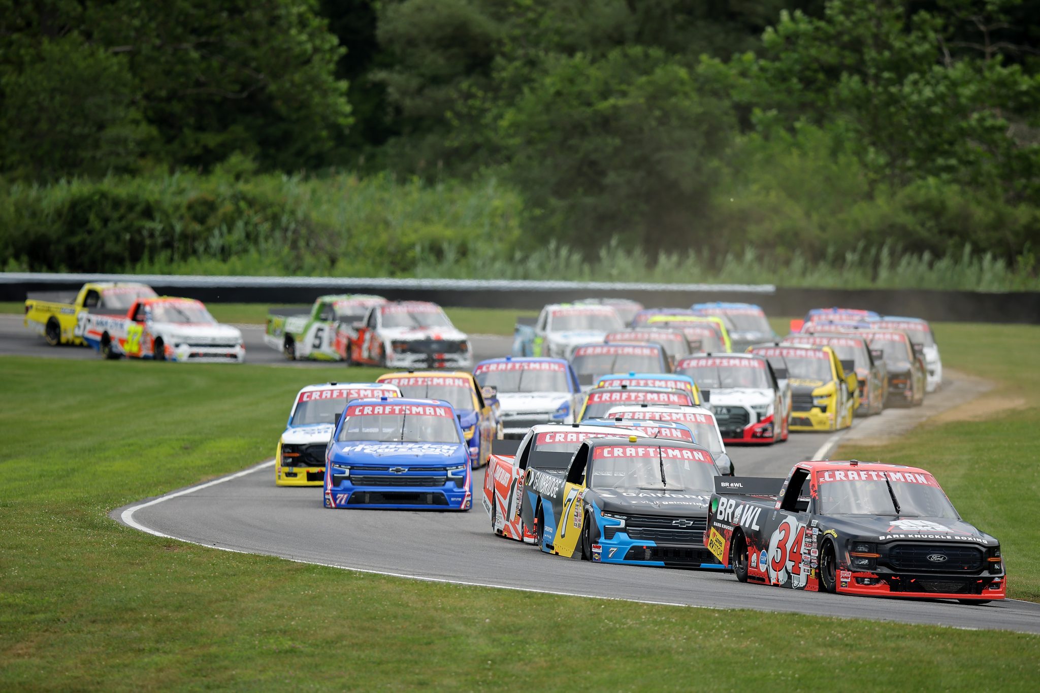 LAKEVILLE, CONNECTICUT - JUNE 28: Layne Riggs, driver of the #34 Bare Knuckle Brawl Ford, and Jordan Taylor, driver of the #7 Gainbridge Chevrolet, race during the NASCAR Craftsman Truck Series LiUNA! 150 at Lime Rock Park on June 28, 2025 in Lakeville, Connecticut. (Photo by Jonathan Bachman/Getty Images) | Getty Images