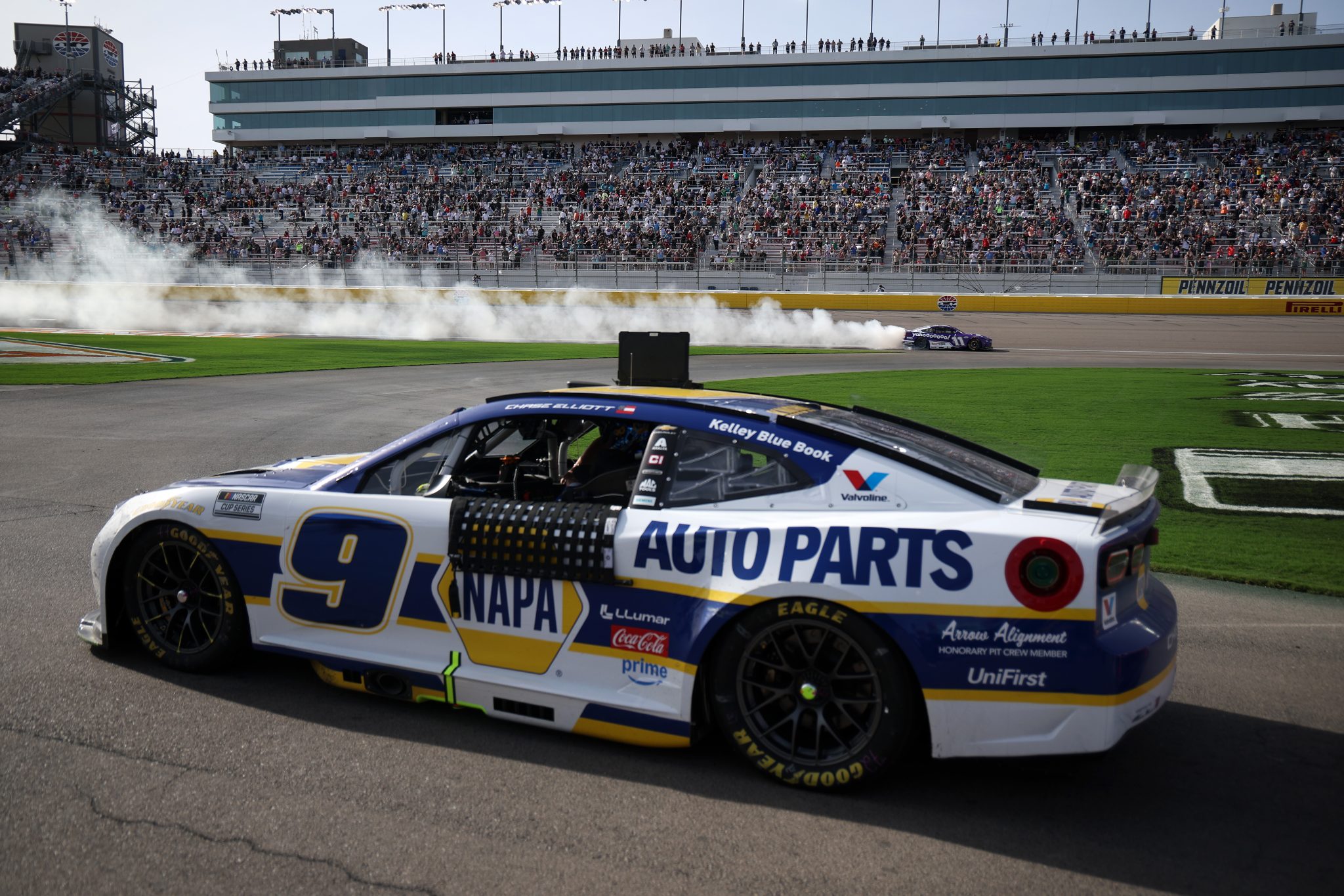 LAS VEGAS, NEVADA - MARCH 15: The #9 NAPA Auto Parts Chevrolet, driven by Chase Elliott sits parked on the grid as Denny Hamlin, driver of the #11 Yahoo! Toyota, celebrates with a burnout after winning the NASCAR Cup Series Pennzoil 400 presented by Jiffy Lube at Las Vegas Motor Speedway on March 15, 2026 in Las Vegas, Nevada. (Photo by Chris Graythen/Getty Images) | Getty Images