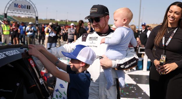 KANSAS CITY, KANSAS - APRIL 19: Tyler Reddick, driver of the #45 Supply House Toyota, son, Beau Reddick places the winner sticker on his car after winning the NASCAR Cup Series AdventHealth 400 at Kansas Speedway on April 19, 2026 in Kansas City, Kansas. (Photo by David Jensen/Getty Images) | Getty Images