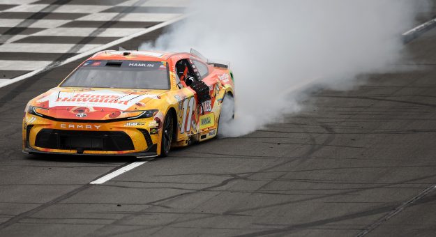 LONG POND, PENNSYLVANIA - JUNE 14: Denny Hamlin, driver of the #11 King's Hawaiian Shake 'Em Bites Toyota, celebrates with a burnout after winning the NASCAR Cup Series Great American Getaway 400 presented by VISITPA at Pocono Raceway on June 14, 2026 in Long Pond, Pennsylvania. (Photo by James Gilbert/Getty Images) | Getty Images
