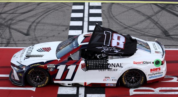 BROOKLYN, MICHIGAN - JUNE 07: Denny Hamlin, driver of the #11 National Debt Relief Toyota, waves an 18 - 8 flag in honor of the late Kyle Busch after winning the NASCAR Cup Series FireKeepers Casino 400 at Michigan International Speedway on June 07, 2026 in Brooklyn, Michigan. (Photo by Brett Farmer/Getty Images) | Getty Images