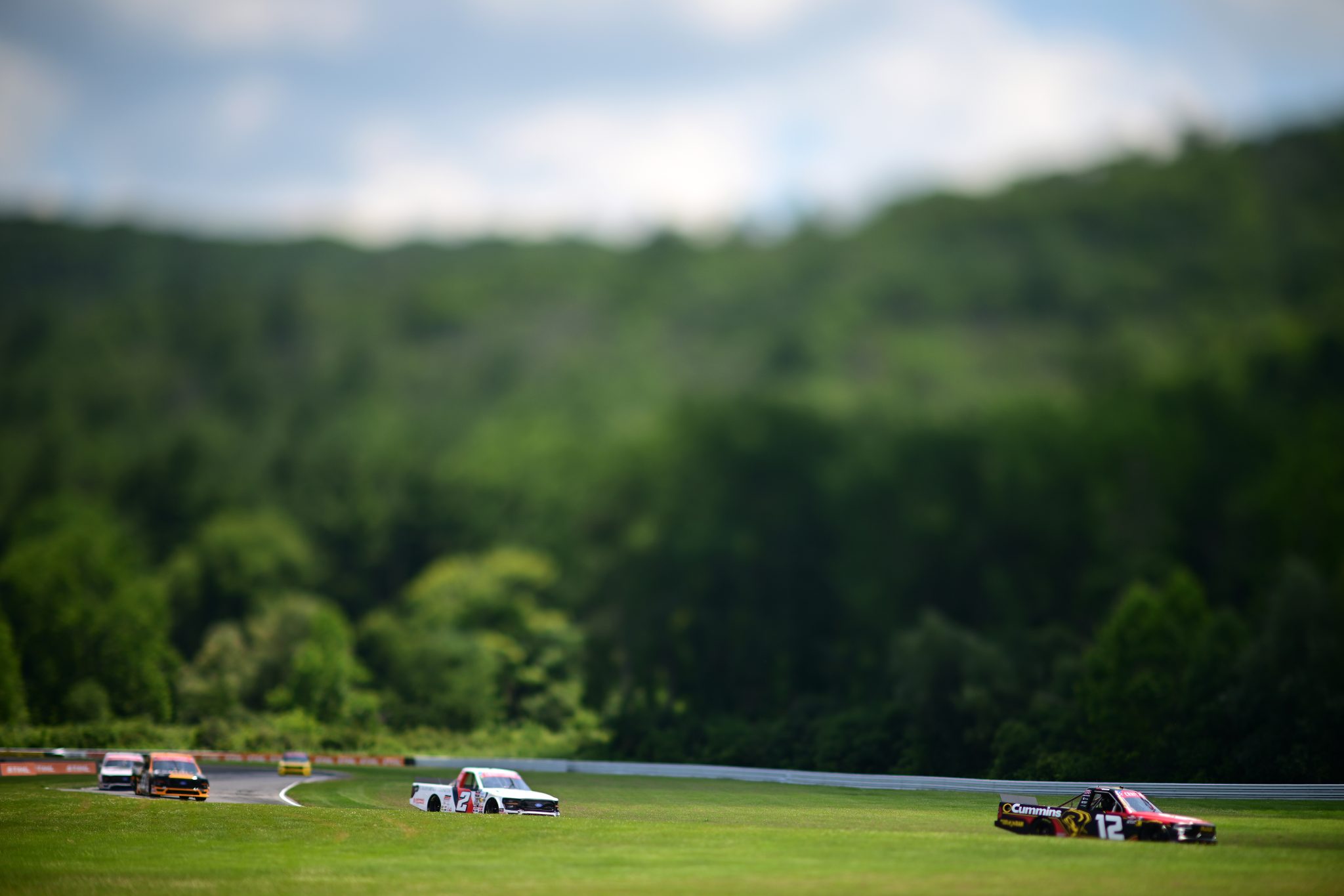 LAKEVILLE, CONNECTICUT - JULY 11: (EDITORS NOTE: Image shot with a tilt-shift lens.) Jackson Lee, driver of the #2 California Closets/Browning Chapman Ford, and Brenden Queen, driver of the #12 Cummins RAM, race during the NASCAR Craftsman Truck Series LiUNA 150 at Lime Rock Park on July 11, 2026 in Lakeville, Connecticut. (Photo by Jaiden Tripi/Getty Images) | Getty Images