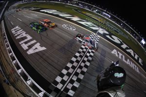 HAMPTON, GEORGIA - JULY 11: Justin Allgaier, driver of the #7 Jarrett Logistics Chevrolet, takes the checkered flag ahead of Carson Kvapil, driver of the #1 Bass Pro Shops Chevrolet, and Parker Retzlaff, driver of the #99 FUNKAWAY Chevrolet, to win the NASCAR O'Reilly Auto Parts Series Focused Health 250 at EchoPark Speedway on July 11, 2026 in Hampton, Georgia. (Photo by Sean Gardner/Getty Images) | Getty Images