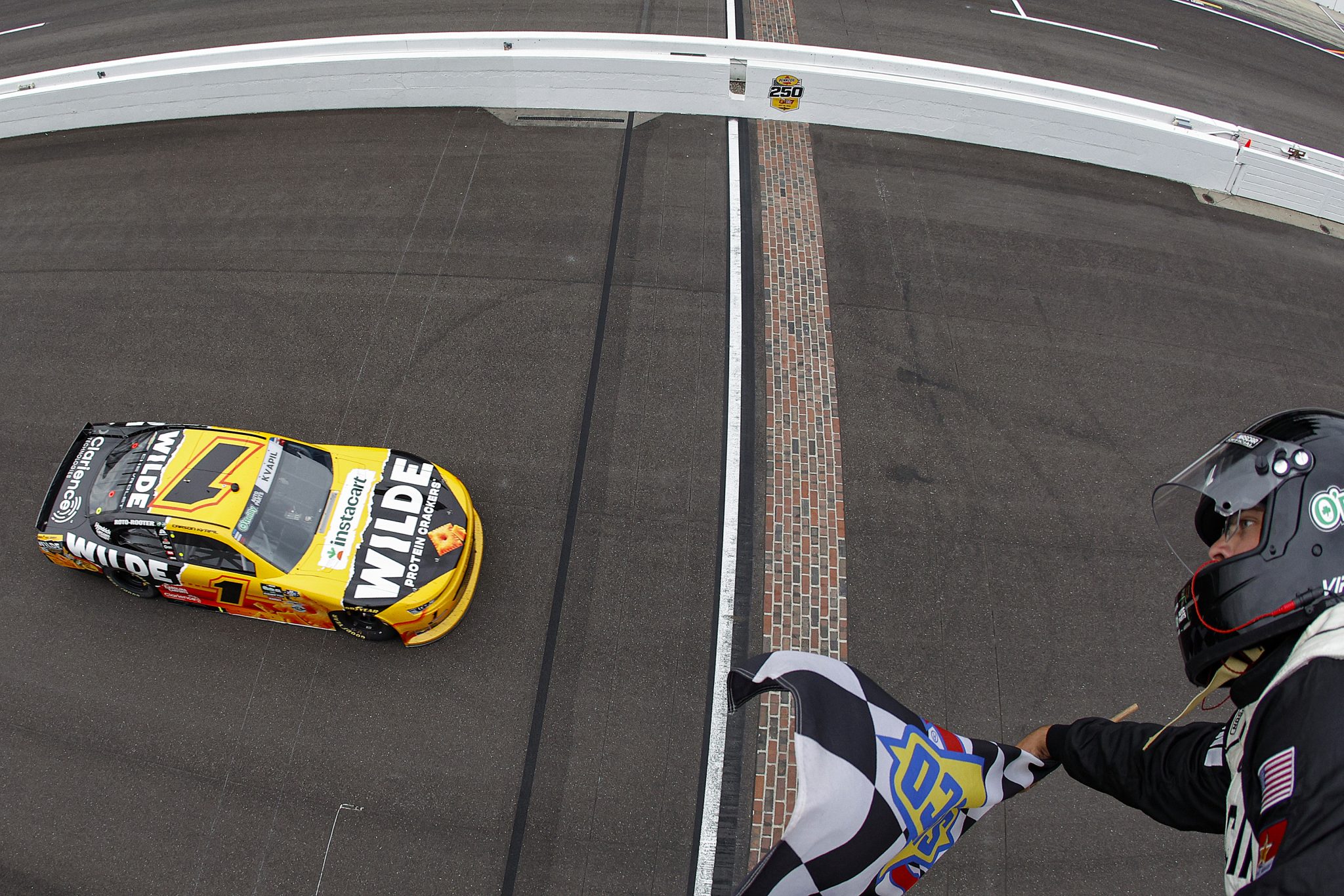 INDIANAPOLIS, INDIANA - JULY 25: Carson Kvapil, driver of the #1 Wilde Protein Crackers Chevrolet, takes the checkered flag to win the NASCAR O'Reilly Auto Parts Series Pennzoil 250 Presented by Take 5 Oil Change at Indianapolis Motor Speedway on July 25, 2026 in Indianapolis, Indiana. (Photo by Sean Gardner/Getty Images) | Getty Images