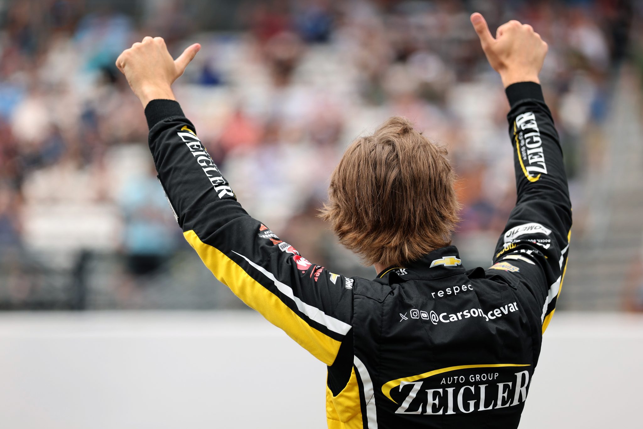 INDIANAPOLIS, INDIANA - JULY 25: Carson Hocevar, driver of the #77 Zeigler Auto Group Chevrolet, gives a thumbs up to the crowd after winning the pole during qualifying for the NASCAR Cup Series Brickyard 400 at Indianapolis Motor Speedway on July 25, 2026 in Indianapolis, Indiana. (Photo by Logan Riely/Getty Images) | Getty Images