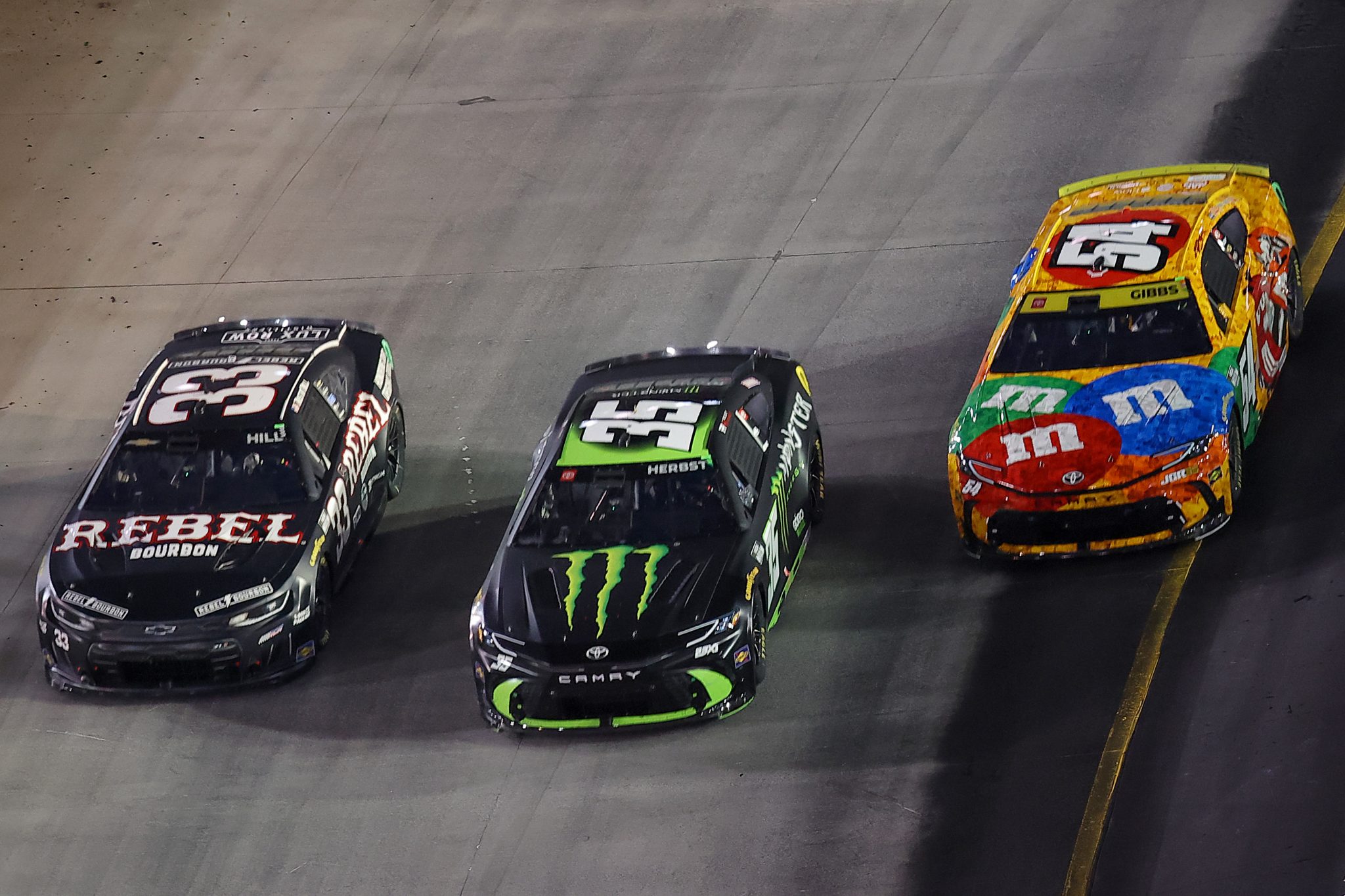 BRISTOL, TENNESSEE - SEPTEMBER 19: Ty Gibbs, driver of the #54 M&M's Kyle Busch Tribute Toyota, Riley Herbst, driver of the #35 Monster Energy Toyota, and Austin Hill, driver of the #33 Rebel Bourbon Chevrolet, race during the NASCAR Cup Series Bass Pro Shops Night Race at Bristol Motor Speedway on September 19, 2026 in Bristol, Tennessee. (Photo by Jonathan Bachman/Getty Images) | Getty Images